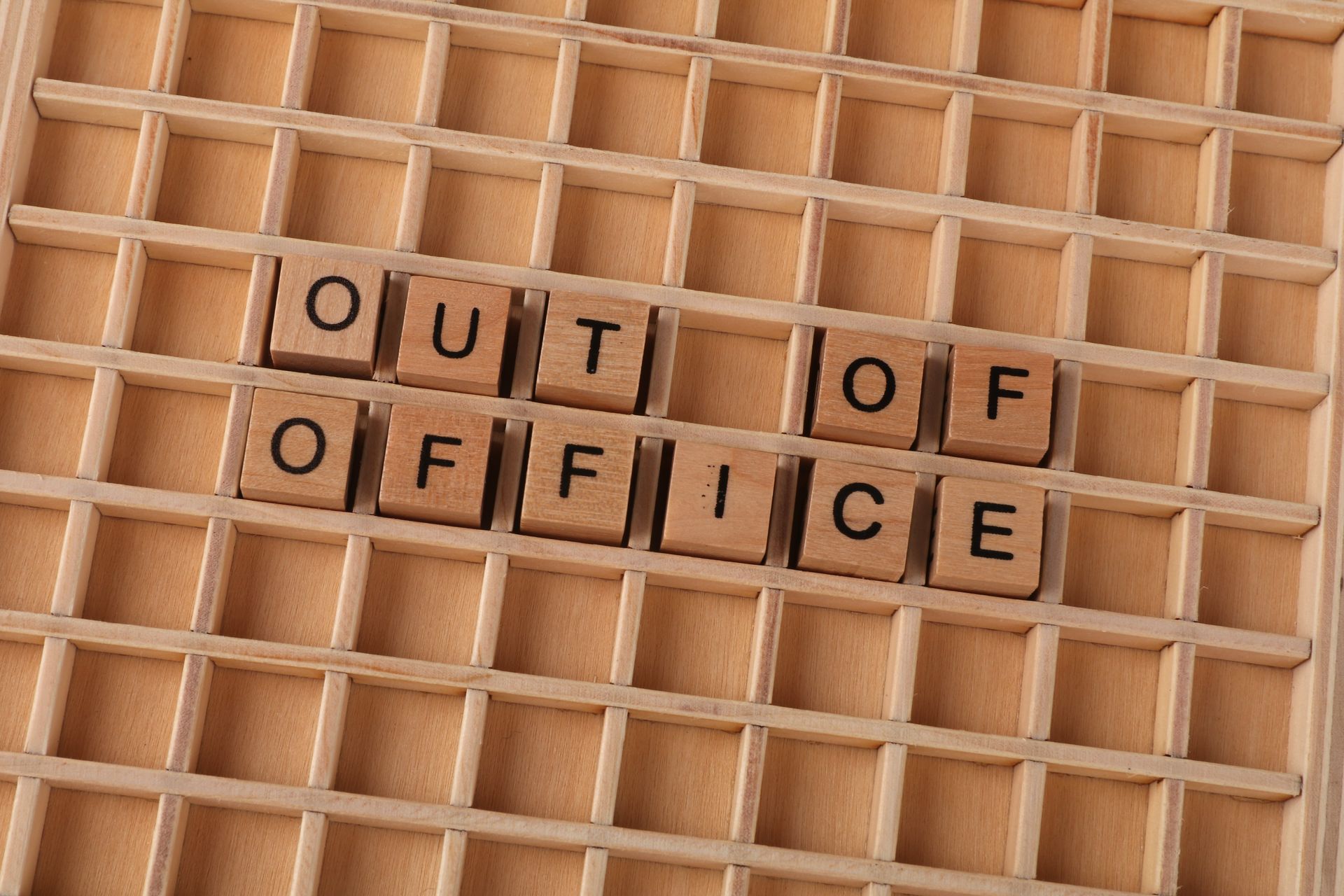 scrabble letters spelling out "out of office"