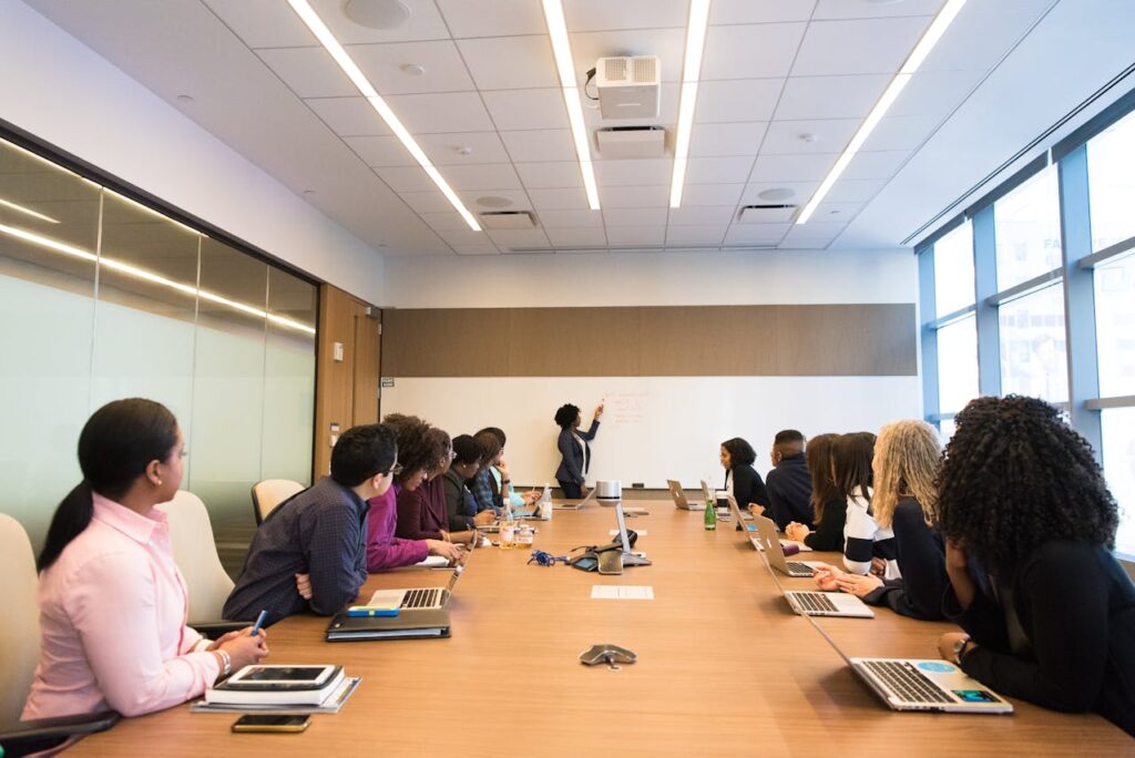 people around a conference table with person presenting at white board